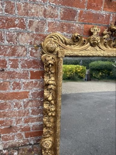 A large nineteenth-century carved giltwood overmantel mirror featuring a prominent central urn crest and floral mouldings. View VII