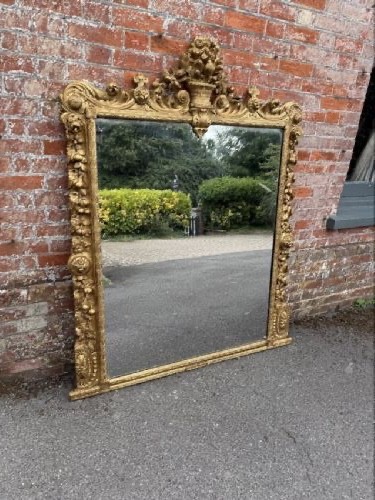 A large nineteenth-century carved giltwood overmantel mirror featuring a prominent central urn crest and floral mouldings. View VIII