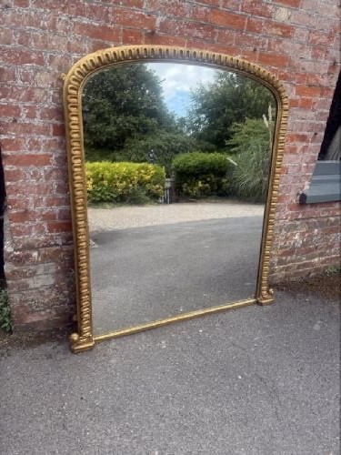 A large 19th-century overmantel mirror featuring an arched gold giltwood frame with fluted moulding detailing and a flat base. View VII