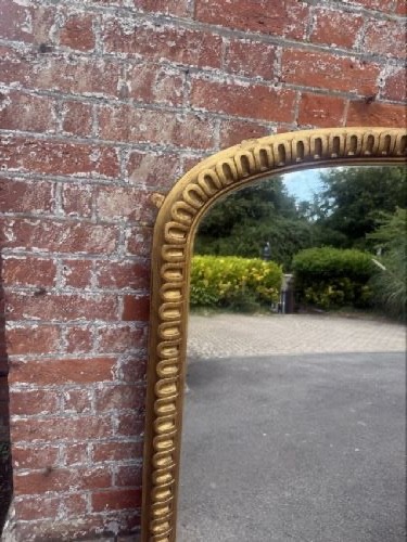 A large 19th-century overmantel mirror featuring an arched gold giltwood frame with fluted moulding detailing and a flat base. View VI