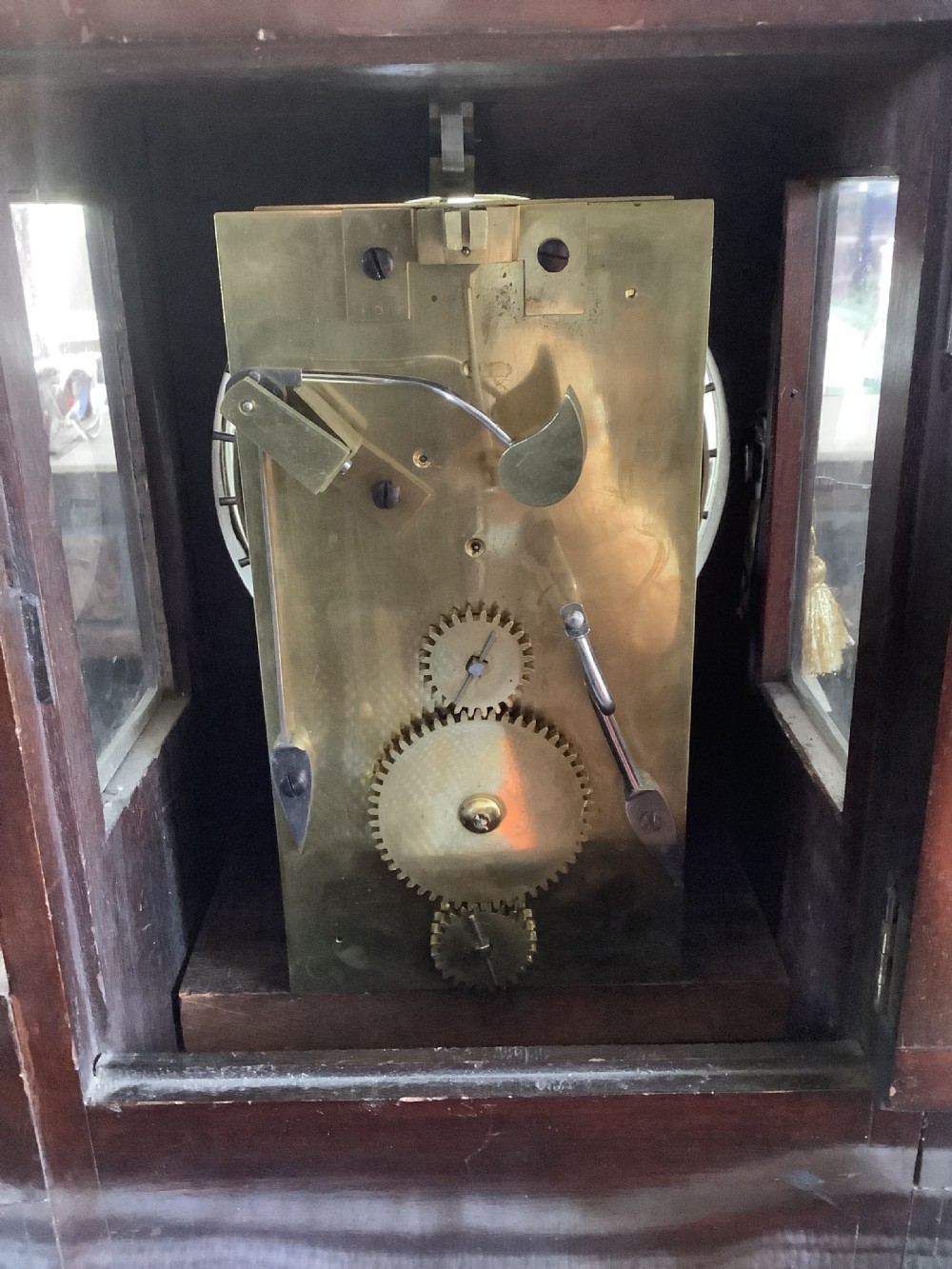 A Victorian mahogany night watchman clock featuring a circular dial with Roman numerals, brass bezel, top mechanism, and carved foliate details at the base. View XI
