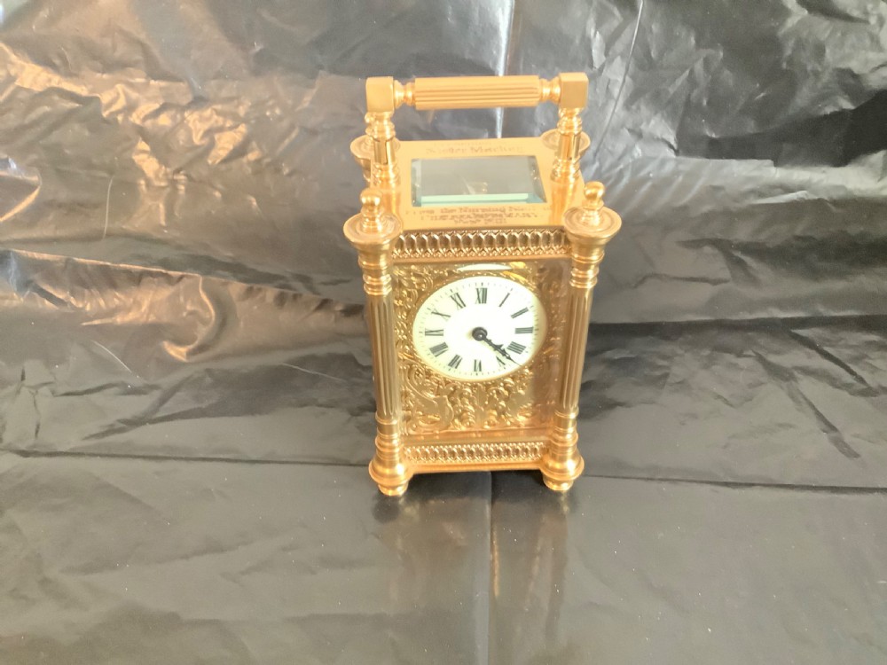 An ornate nineteenth-century French gilt brass carriage clock featuring fluted corner columns, intricate leaf scrollwork, a white enamel dial with Roman numerals, and a hinged top handle. View V
