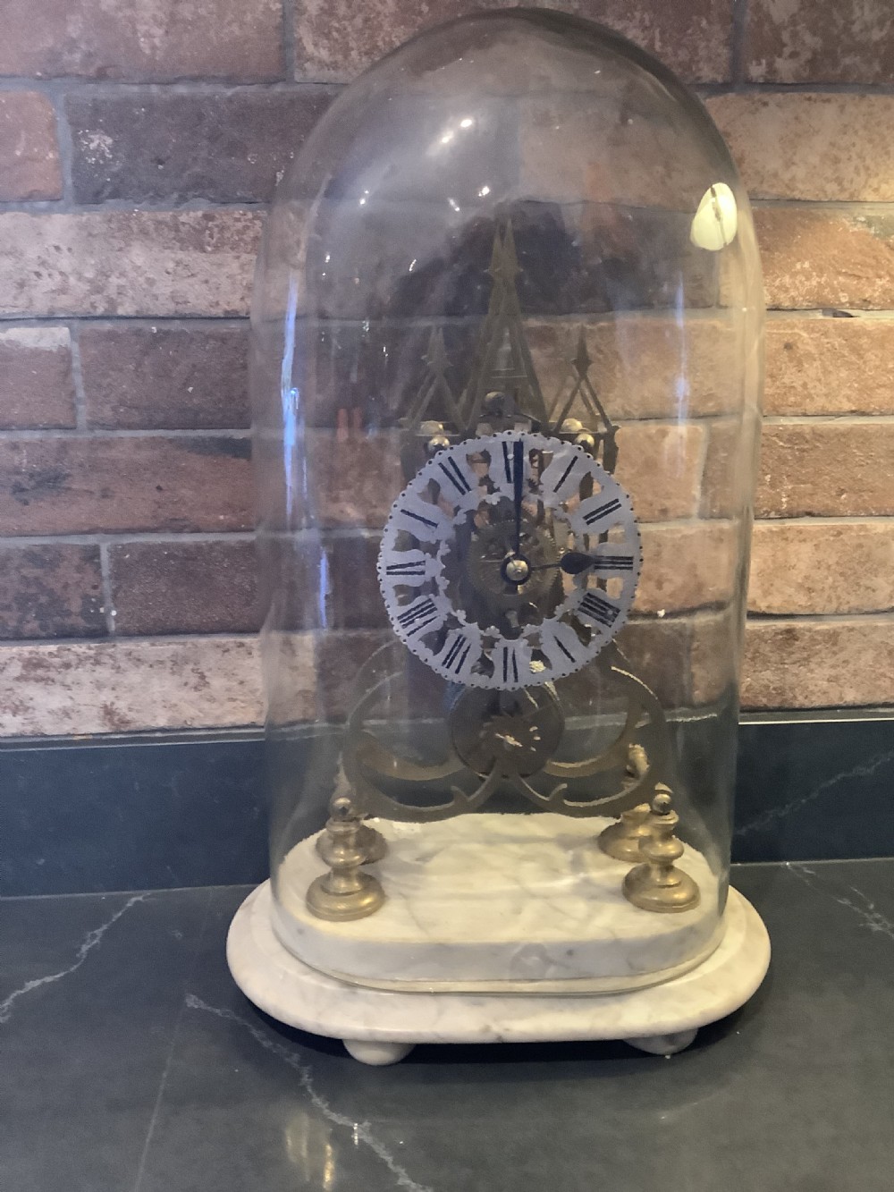 A Victorian brass skeleton clock featuring gothic architectural spires and a pierced silvered dial mounted on an oval white marble base. View V