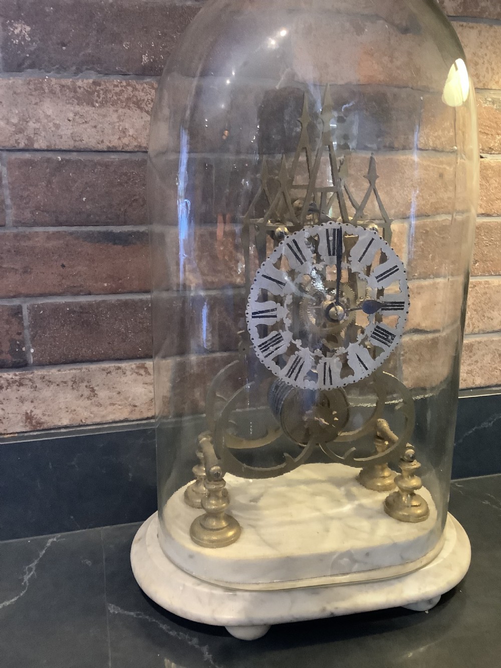 A Victorian brass skeleton clock featuring gothic architectural spires and a pierced silvered dial mounted on an oval white marble base. View VI