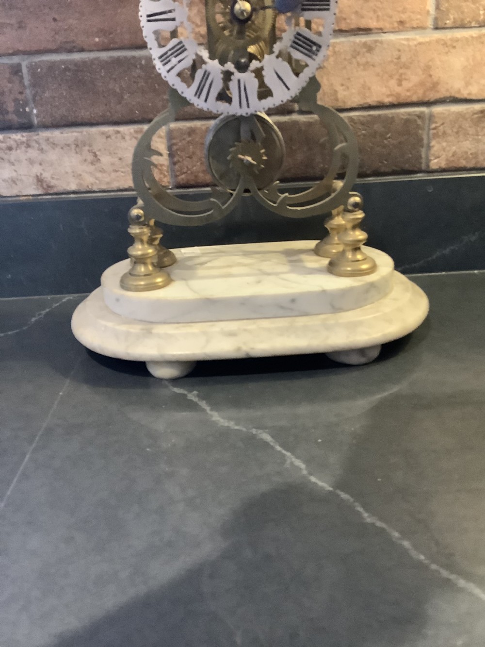 A Victorian brass skeleton clock featuring gothic architectural spires and a pierced silvered dial mounted on an oval white marble base. View XI