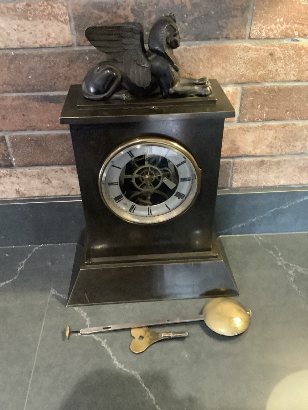 A Victorian patinated bronze mantel clock featuring an open skeleton dial signed Frodsham Gracechurch Street alongside a brass pendulum and winding key. View II