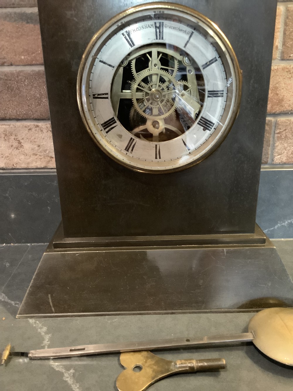 A Victorian patinated bronze mantel clock featuring an open skeleton dial signed Frodsham Gracechurch Street alongside a brass pendulum and winding key. View III