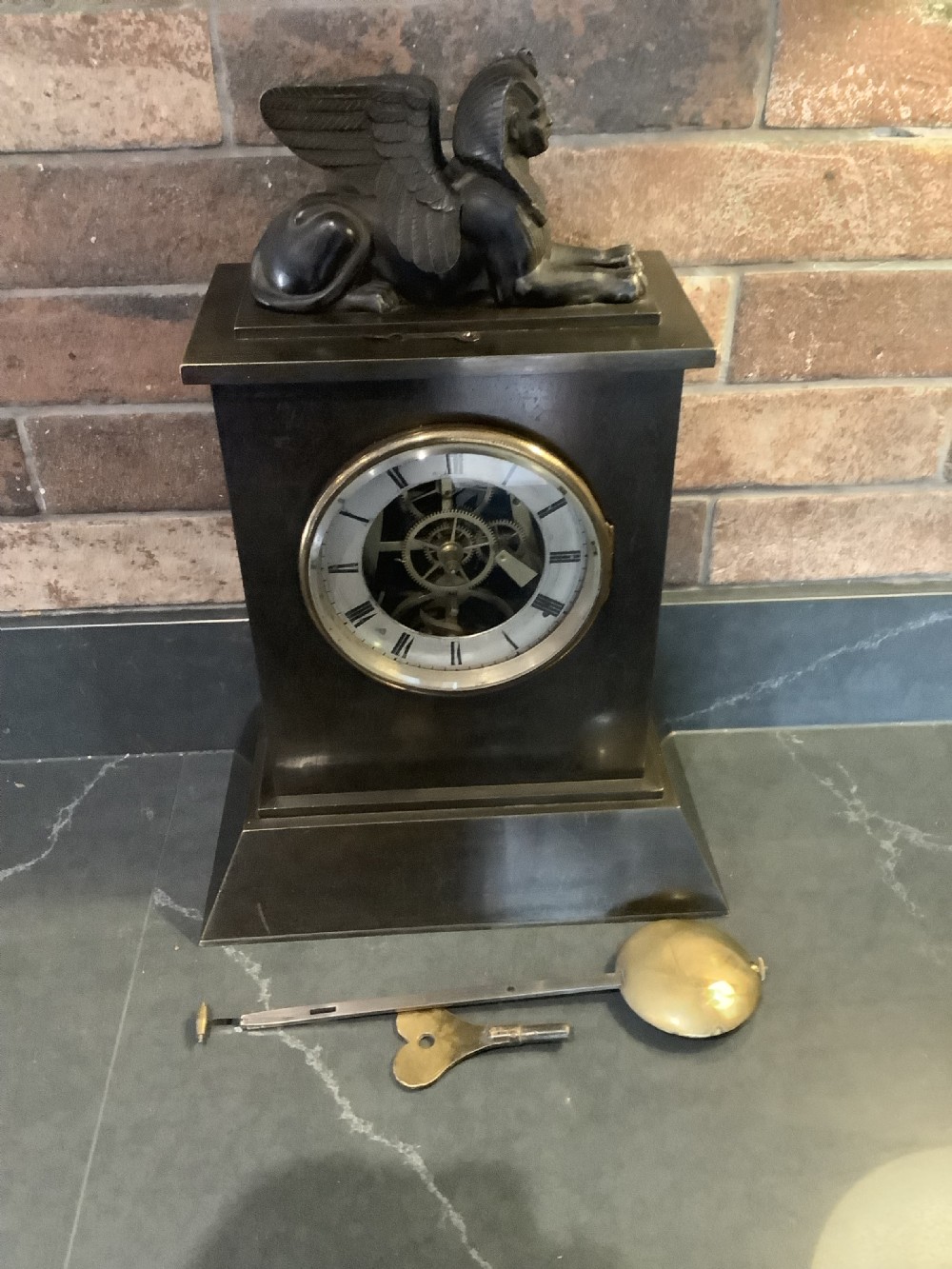 A Victorian patinated bronze mantel clock featuring an open skeleton dial signed Frodsham Gracechurch Street alongside a brass pendulum and winding key. View XIV