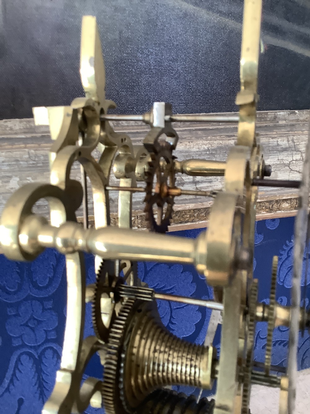 A Victorian brass skeleton clock featuring an openwork frame, pierced chapter ring with Roman numerals, and a white marble plinth base. View XI