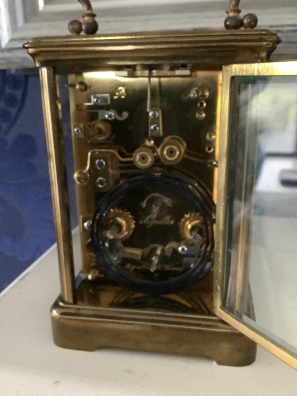 An antique French brass carriage clock featuring a white enamel dial with Roman numerals, a subsidiary dial, and an overhead carrying handle. View IV