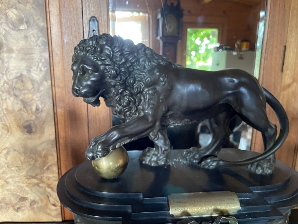 An antique French mantel clock garniture set featuring a black stone clock topped with a bronze lion alongside two matching classical urns. View VI
