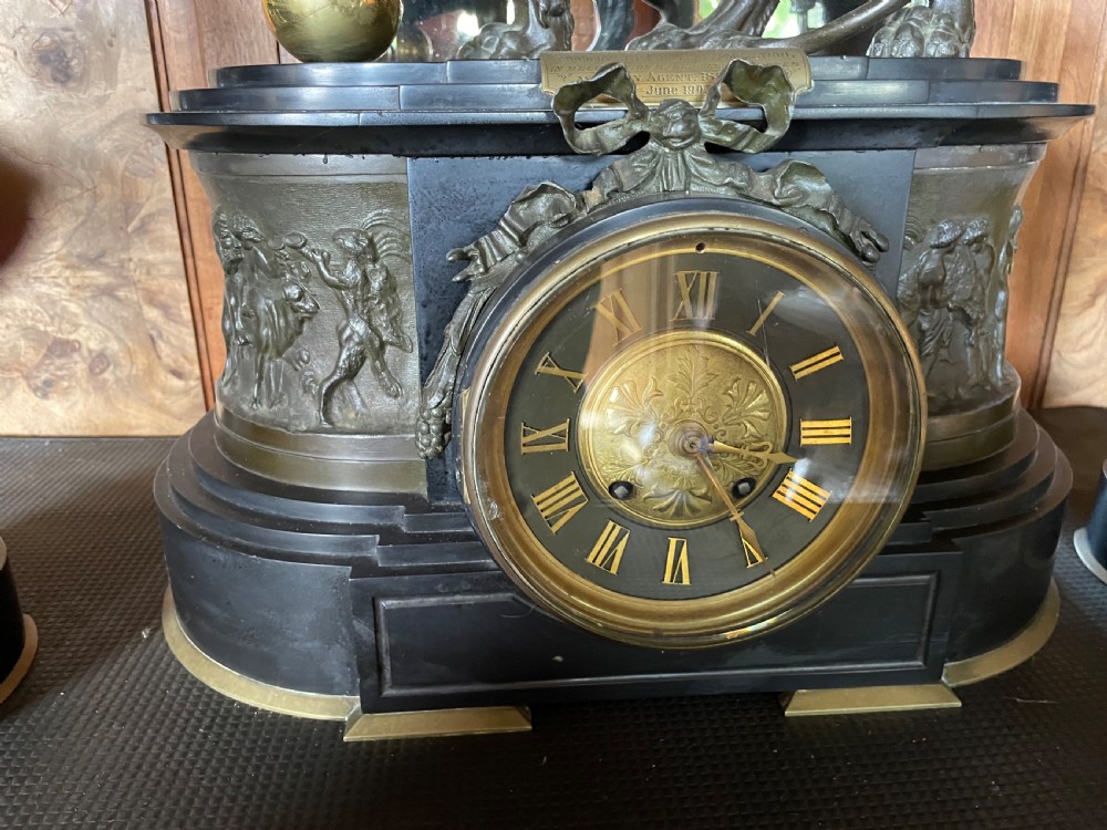 An antique French mantel clock garniture set featuring a black stone clock topped with a bronze lion alongside two matching classical urns. View VIII