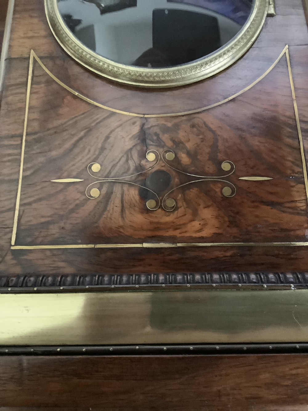 A Regency period wooden table clock with brass inlay, a pediment top, brass lion-head side handles, and a white dial displaying Roman numerals. View V
