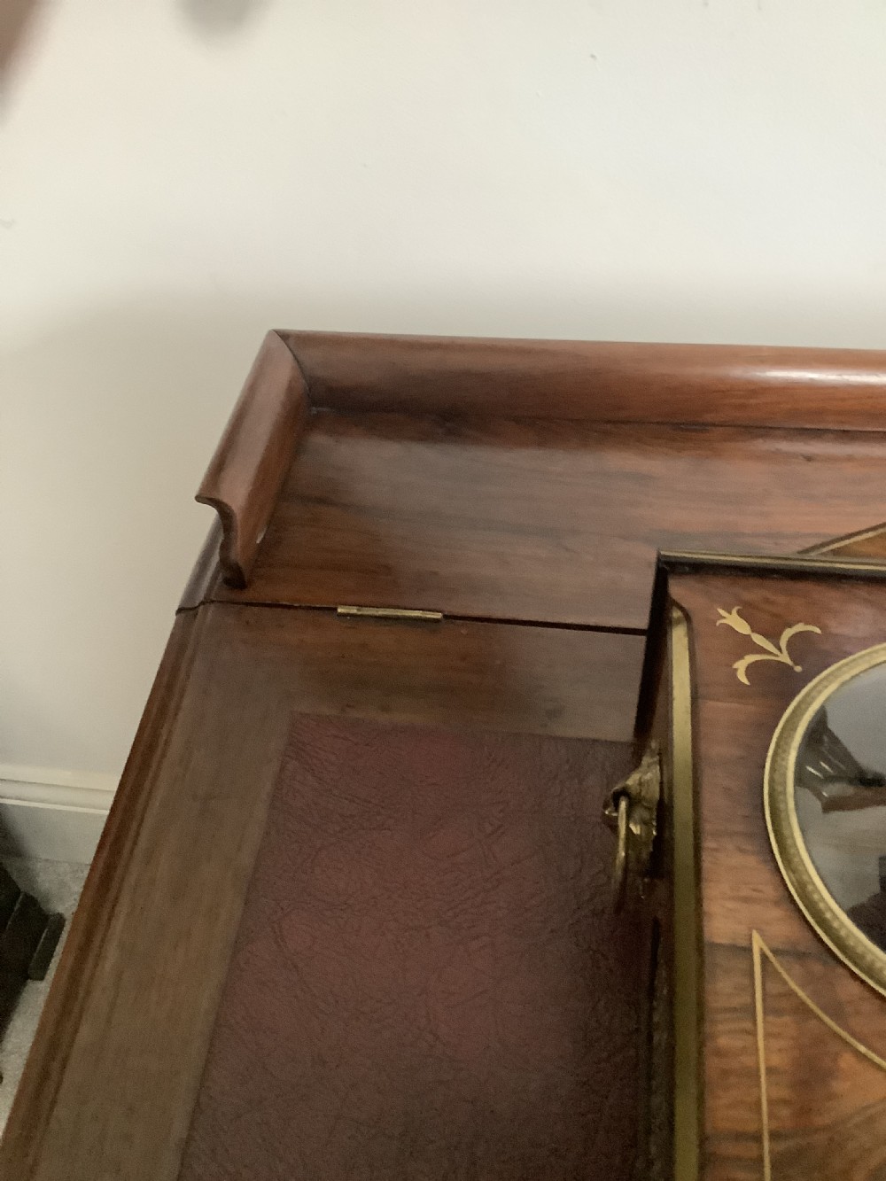 A Regency period wooden table clock with brass inlay, a pediment top, brass lion-head side handles, and a white dial displaying Roman numerals. View X