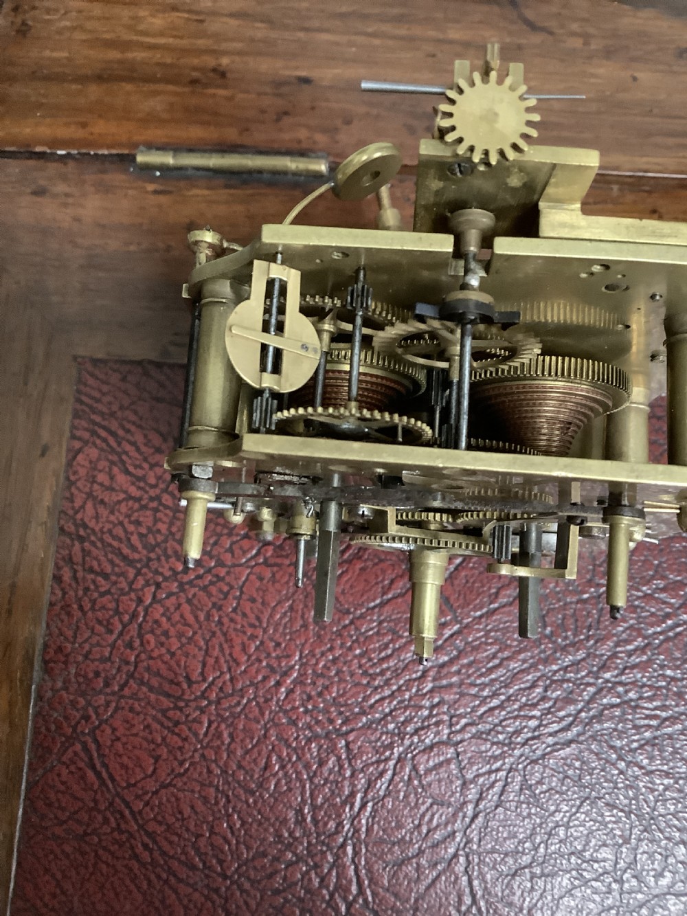 A Regency period wooden table clock with brass inlay, a pediment top, brass lion-head side handles, and a white dial displaying Roman numerals. View XIV