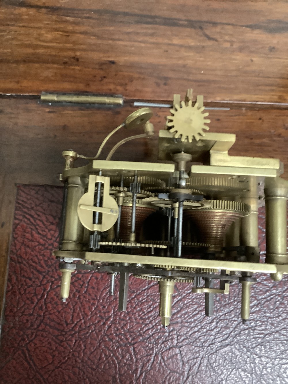 A Regency period wooden table clock with brass inlay, a pediment top, brass lion-head side handles, and a white dial displaying Roman numerals. View XV