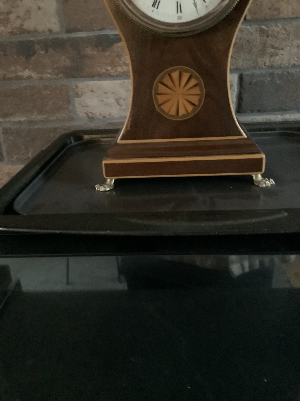 An antique French balloon-shaped wooden mantel clock featuring mahogany veneer with satinwood starburst marquetry inlay, a white dial with Roman numerals, and brass bracket feet. View III