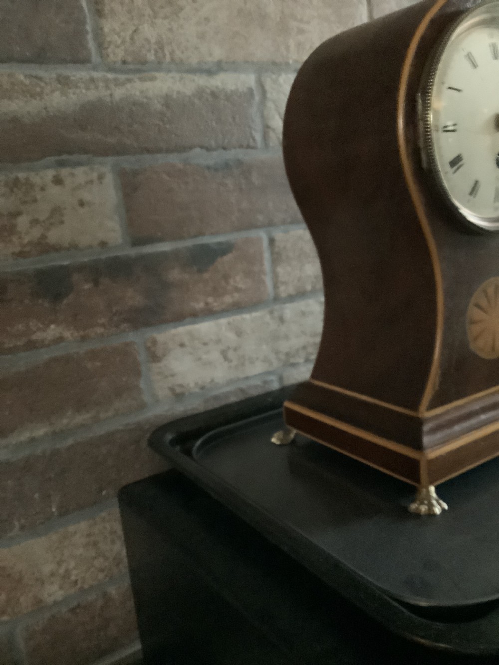 An antique French balloon-shaped wooden mantel clock featuring mahogany veneer with satinwood starburst marquetry inlay, a white dial with Roman numerals, and brass bracket feet. View V