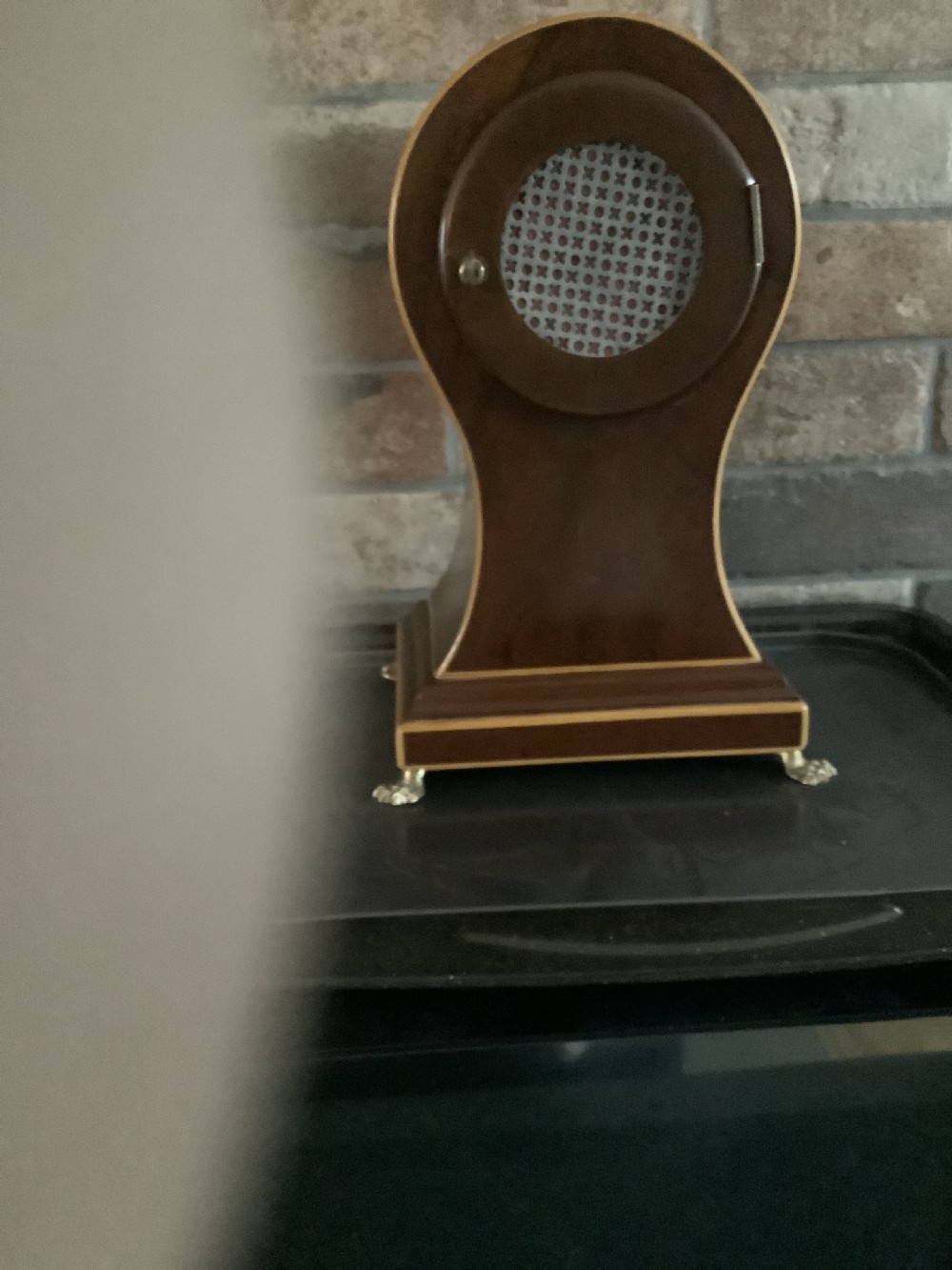 An antique French balloon-shaped wooden mantel clock featuring mahogany veneer with satinwood starburst marquetry inlay, a white dial with Roman numerals, and brass bracket feet. View VI