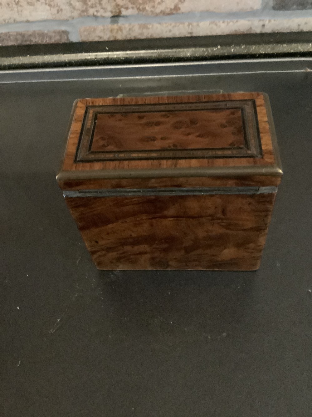 An antique pocket watch with a white enamel dial and Roman numerals displayed open inside a velvet-lined wooden presentation box. View IV