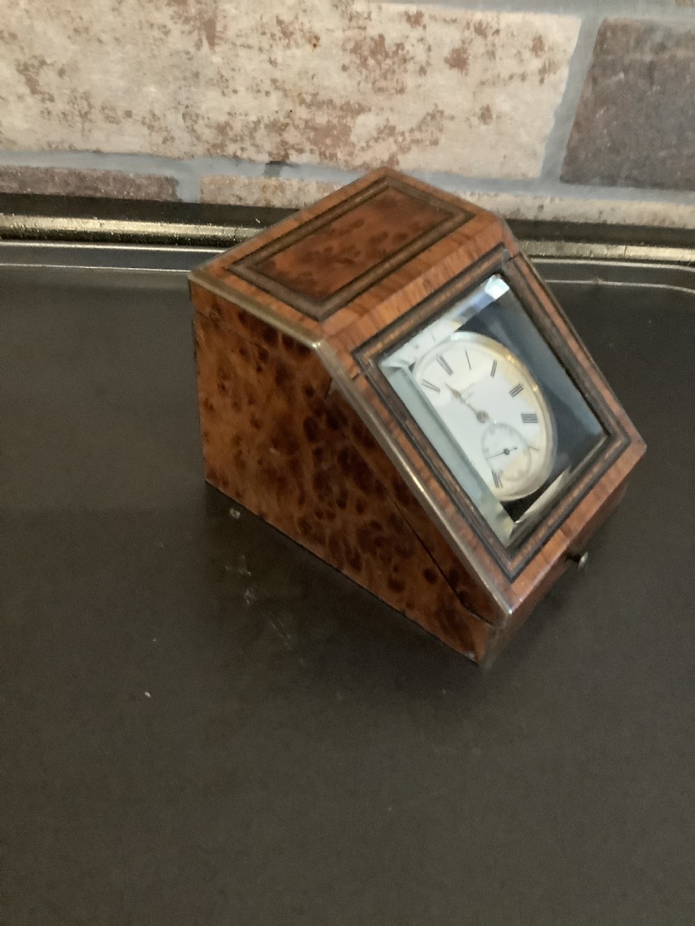 An antique pocket watch with a white enamel dial and Roman numerals displayed open inside a velvet-lined wooden presentation box. View VI