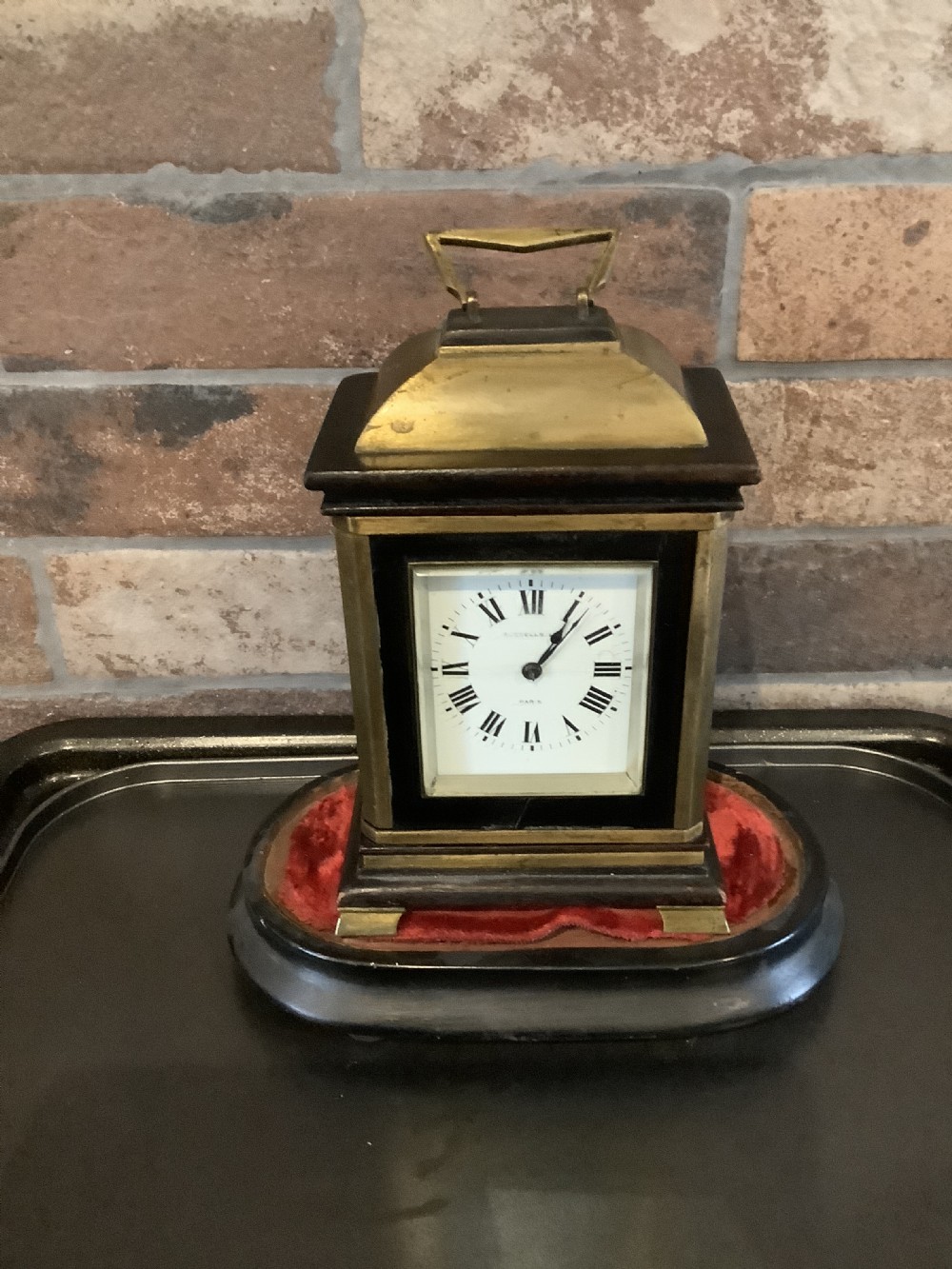 A nineteenth-century French striking mantel clock set within a dark wood and brass-trimmed case with a white enamel dial displaying Roman numerals. View IV