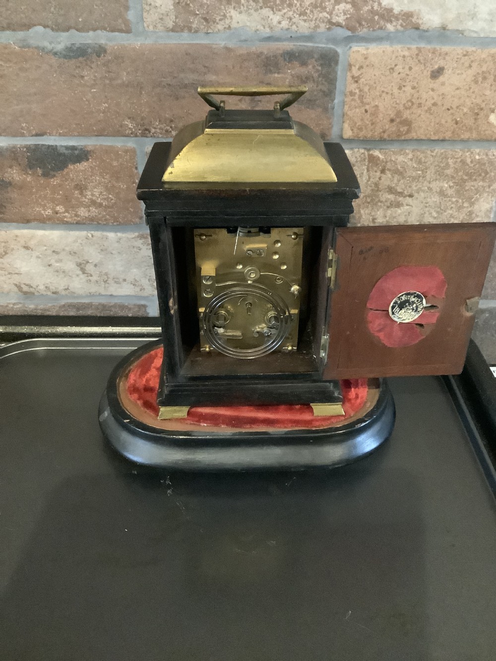 A nineteenth-century French striking mantel clock set within a dark wood and brass-trimmed case with a white enamel dial displaying Roman numerals. View V