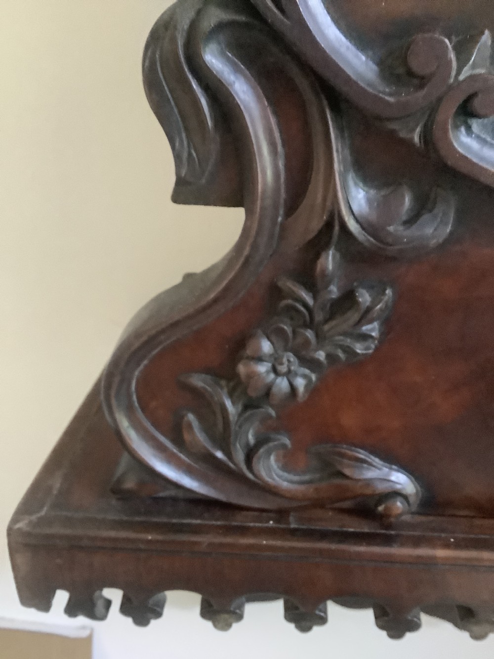 A Victorian carved mahogany fusee wall clock featuring an off-white circular dial with Roman numerals, brass bezel, and ornate matching wooden bracket support. View III