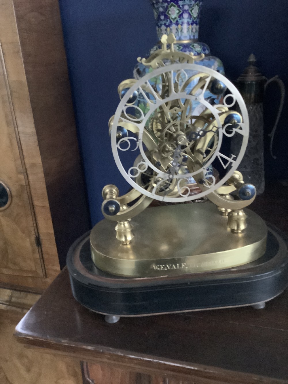 A Victorian brass skeleton clock featuring an openwork movement, a silvered chapter ring with Arabic numerals, and a engraved brass plinth resting on an ebonised oval base.