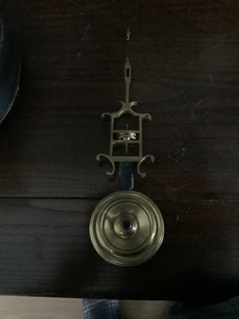 A Victorian brass skeleton clock featuring an openwork movement, a silvered chapter ring with Arabic numerals, and a engraved brass plinth resting on an ebonised oval base. View VII