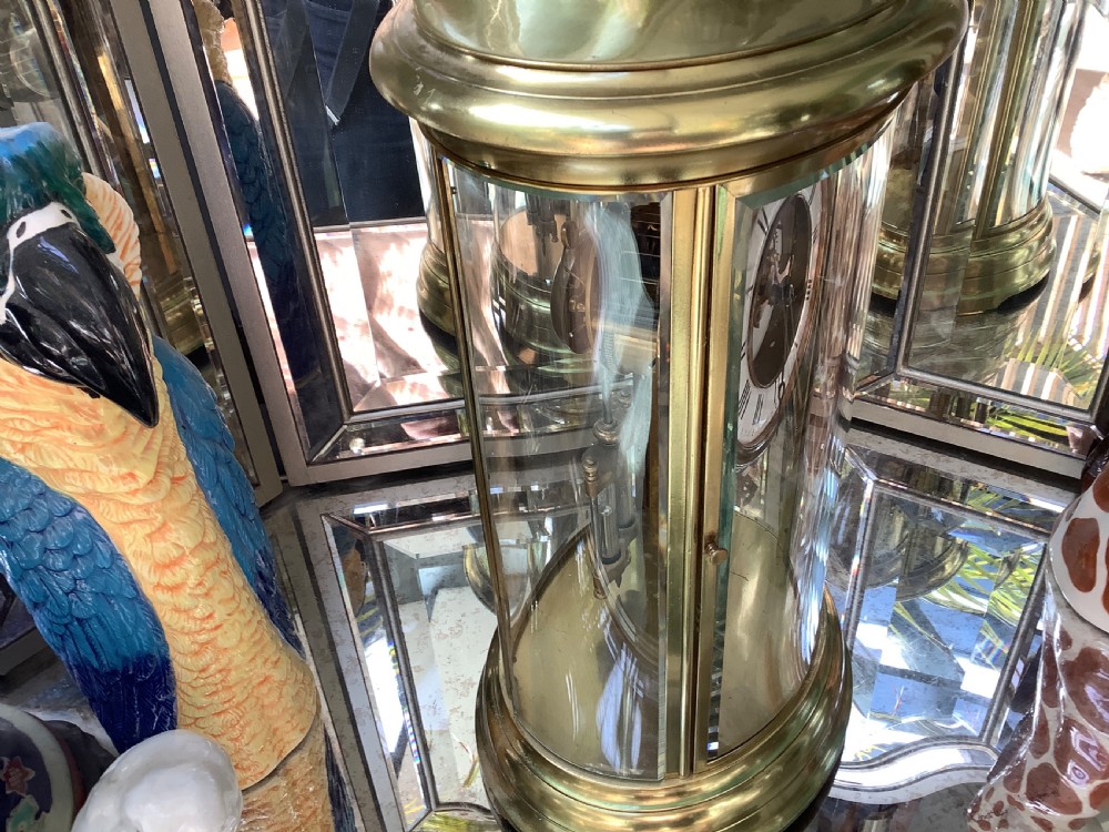 An oval brass four glass mantel clock featuring an enamel dial with Roman numerals and visible internal escapement mechanism. View II