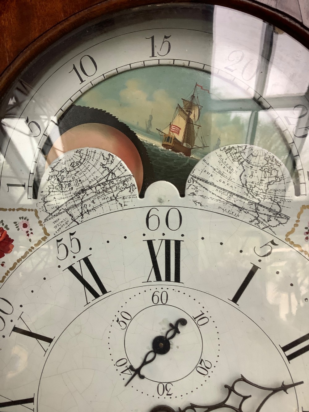 An antique mahogany grandfather clock featuring a painted dial with Roman numerals, a swan-neck pediment, reeded columns, and a polished timber trunk door. View VII