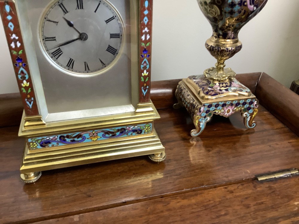 A three-piece French champleve enamel clock garniture set featuring an arched central clock flanked by two matching ornamental vases on gilt bases. View VI