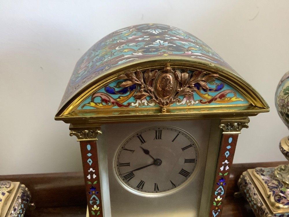 A three-piece French champleve enamel clock garniture set featuring an arched central clock flanked by two matching ornamental vases on gilt bases. View VIII