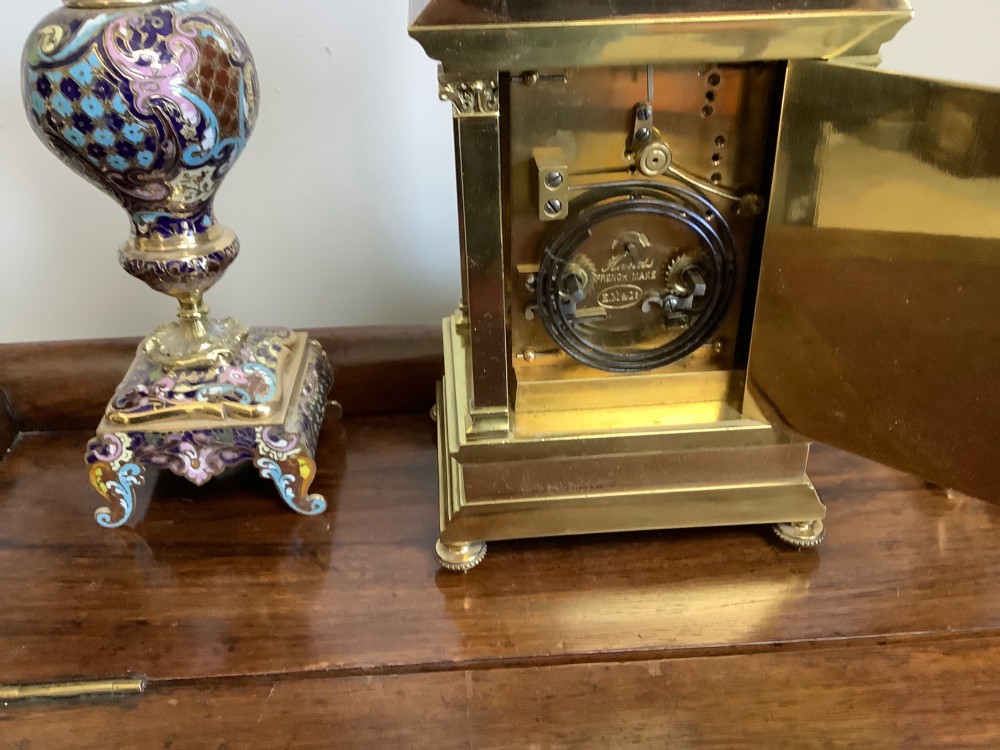 A three-piece French champleve enamel clock garniture set featuring an arched central clock flanked by two matching ornamental vases on gilt bases. View XI