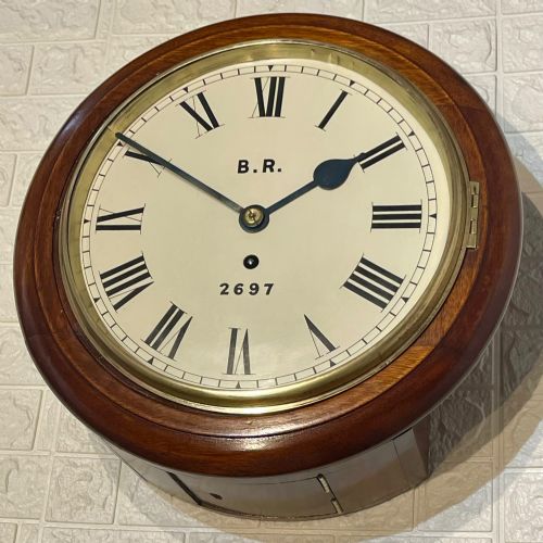 fig 4. A circular antique mahogany fusee wall clock featuring a cream dial marked B.R., Roman numerals, black hands, and a brass bezel.
