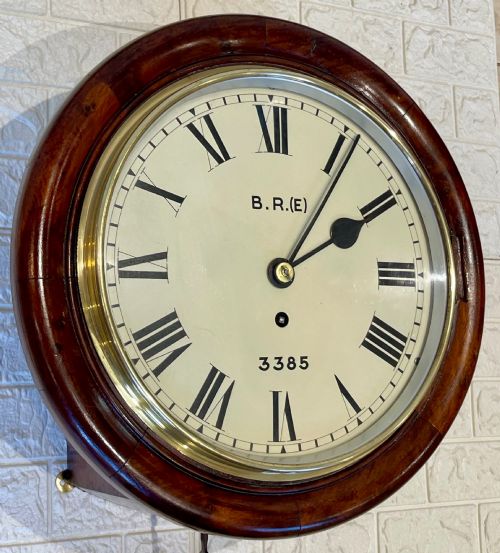fig 1. A circular antique mahogany railway dial wall clock with a painted off-white face, Roman numerals, brass bezel, and British Railways marking.