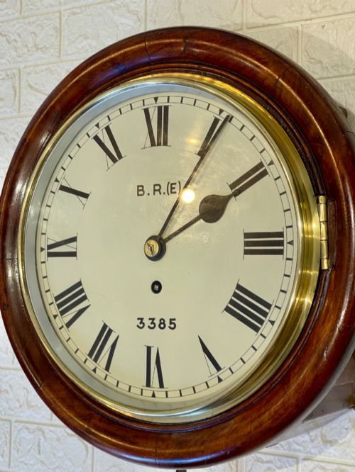 fig 2. A circular antique mahogany railway dial wall clock with a painted off-white face, Roman numerals, brass bezel, and British Railways marking.