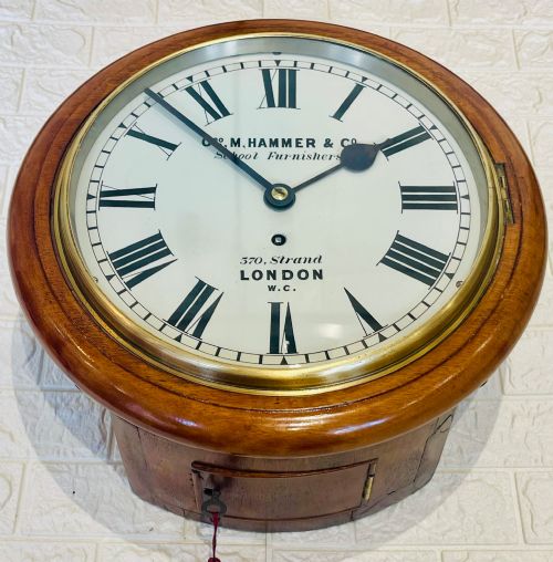 fig 2. A circular Victorian mahogany wall clock featuring a white dial with black Roman numerals, a polished brass bezel, and London maker inscription.