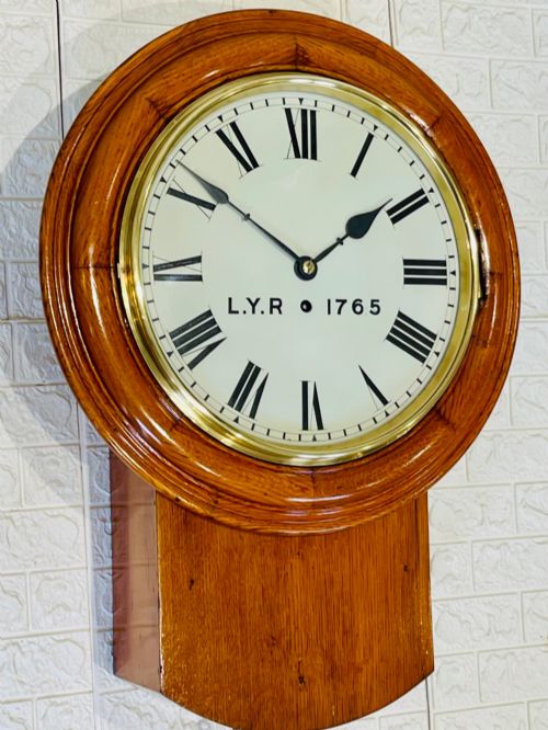 fig 1. An antique oak drop dial wall clock featuring a white face with Roman numerals, marked L.Y.R 1765 with a brass bezel.