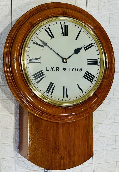 fig 2. An antique oak drop dial wall clock featuring a white face with Roman numerals, marked L.Y.R 1765 with a brass bezel.