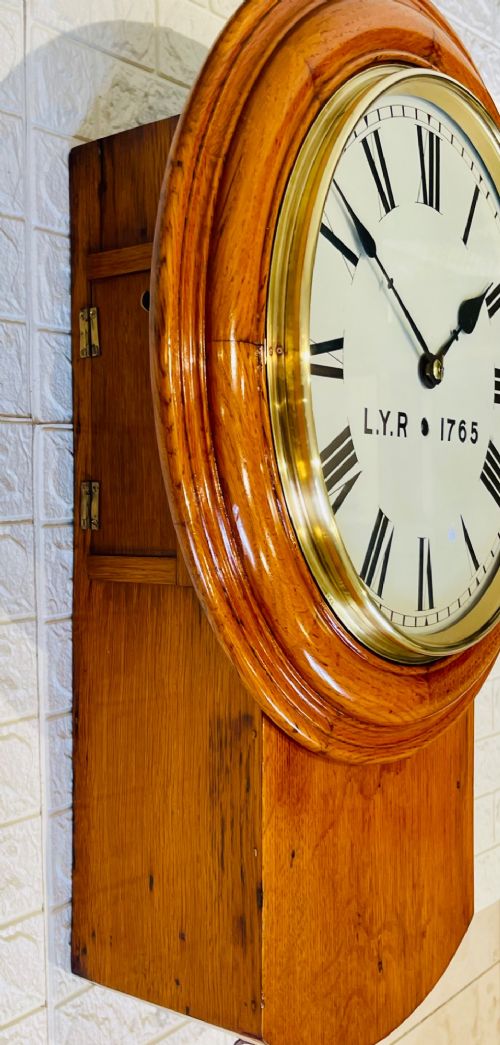An antique oak drop dial wall clock featuring a white face with Roman numerals, marked L.Y.R 1765 with a brass bezel. View X