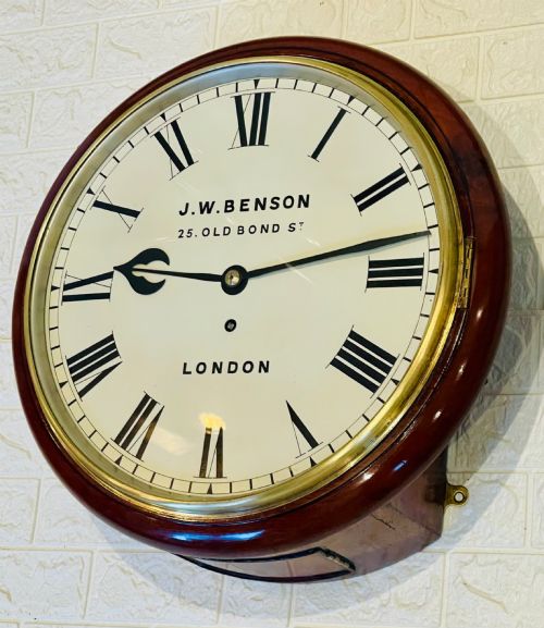 fig 3. A circular mahogany fusee wall clock featuring a white dial face with black Roman numerals, brass bezel, and J. W. Benson London markings.