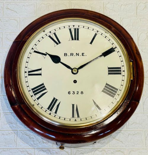 fig 1. A circular Victorian railway dial clock with a dark mahogany frame, brass bezel, and off-white dial featuring black Roman numerals.