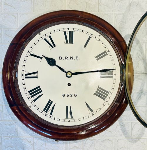 fig 3. A circular Victorian railway dial clock with a dark mahogany frame, brass bezel, and off-white dial featuring black Roman numerals.