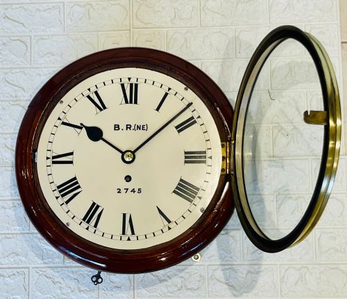 fig 4. A circular 10-inch railway dial wall clock featuring a turned mahogany wooden surround, a brass bezel, and a cream dial marked B.R.(NE) with black Roman numerals.