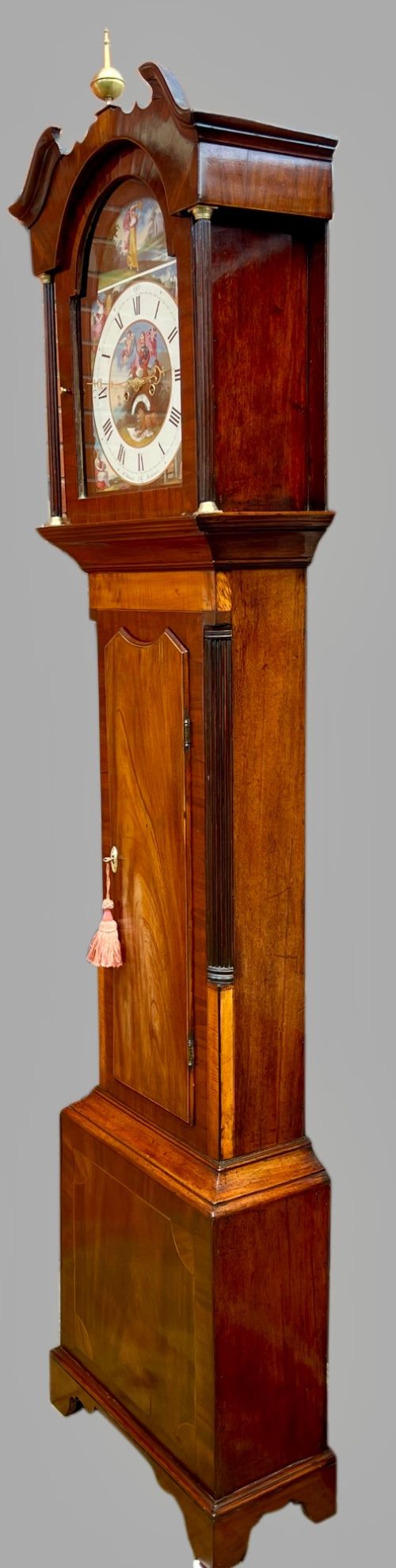 A tall Regency mahogany longcase clock featuring a swan-neck hood pediment, brass finial, fluted columns, and a hand-painted dial with figurative scenes. View XIV