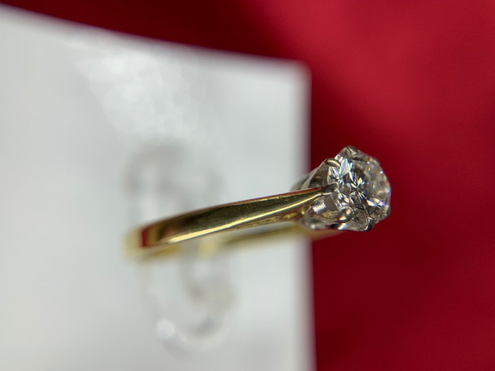 A single round diamond set in platinum claws on an 18ct yellow gold band. View IV