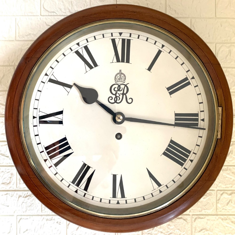 A circular antique fusee wall clock featuring a warm mahogany wooden surround, a brass glass bezel, and a white painted dial with black Roman numerals and a GVR royal cypher monogram.