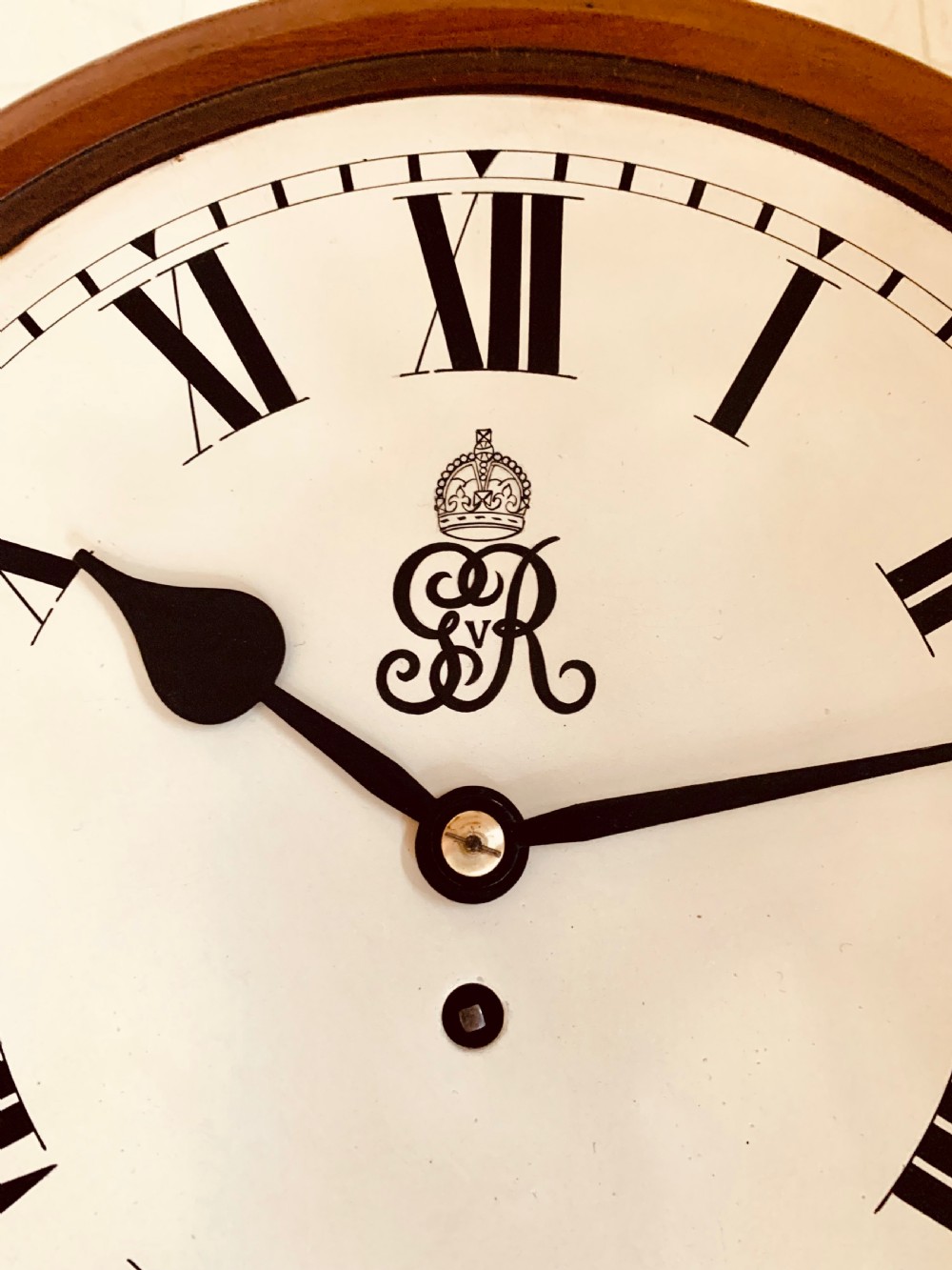 A circular antique fusee wall clock featuring a warm mahogany wooden surround, a brass glass bezel, and a white painted dial with black Roman numerals and a GVR royal cypher monogram. View II